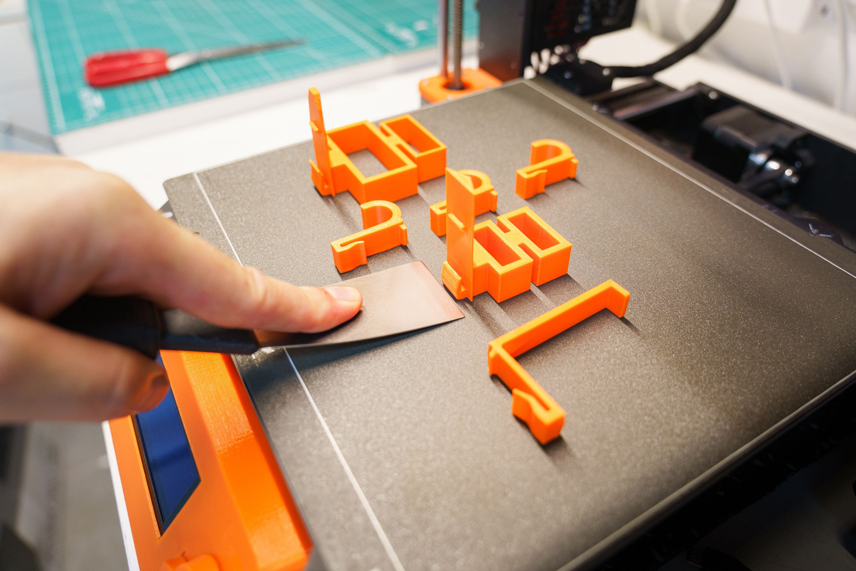 Close-up of orange 3D-printed parts on a printer bed at Elemental Crafts 3D